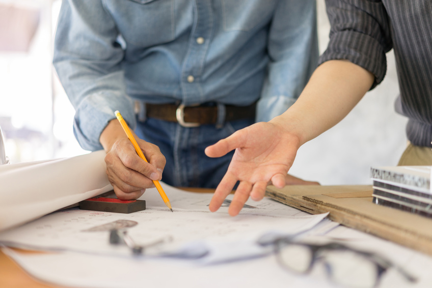 two people indicating at architectural plans