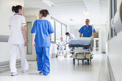 Male nurse pushing stretcher gurney bed in hospital corridor